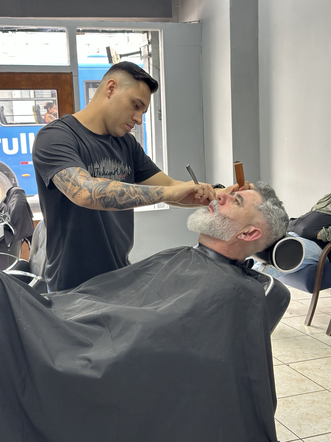 Barbeiro realizando atendimento de barba na Barbearia Calcki